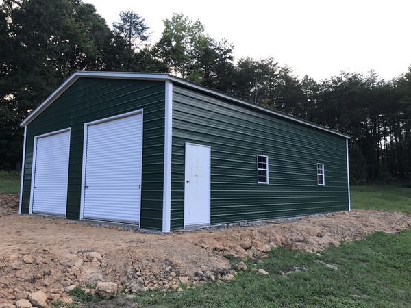 green metal building with two garage doors and side door and windows